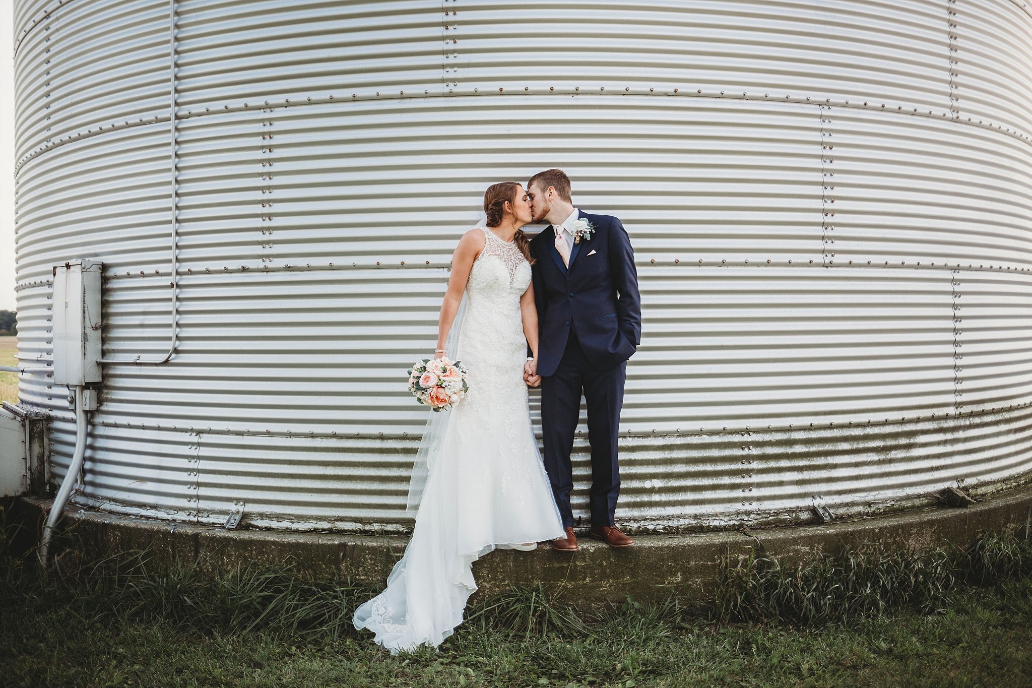 bride and grrom kissing on a grain bin at their meadow springs manor wedding in Francesville, Indiana