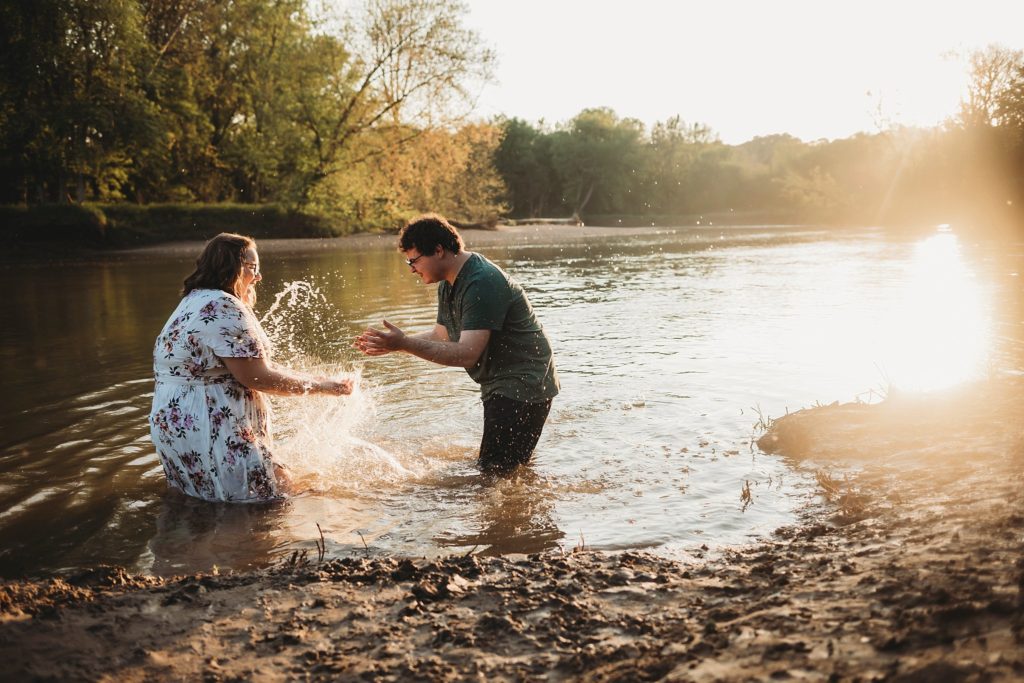 engagement pictures in Lafayette Indiana - man and woman splashing water on each other at romantic engagement photos at Wildcat Creek Park during sunset