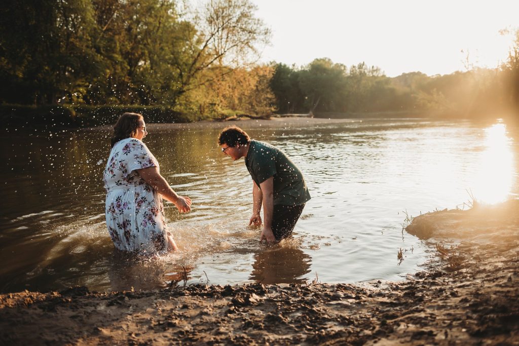 engagement pictures in Lafayette Indiana - man and woman splashing water on each other at romantic engagement photos at Wildcat Creek Park during sunset