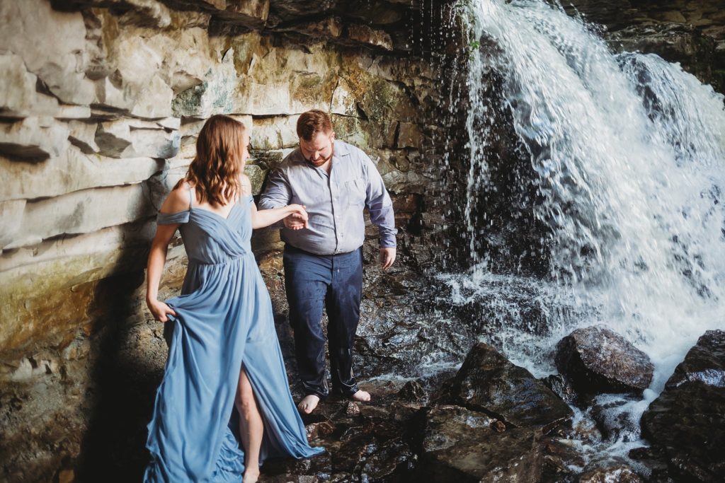 Man and woman climbing under a waterfall at McCormick's Creek State Park in Spencer, Indiana after their Indiana Elopement.