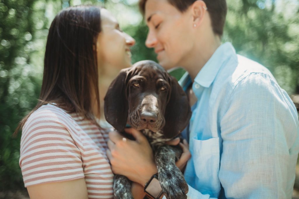 LGBTQ couple holds puppy while leaning in for a kissing at their Lafayette, Indiana couples session 