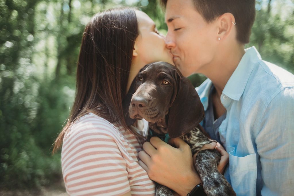 LGBTQ couple holds puppy while kissing at their Lafayette, Indiana couples session 