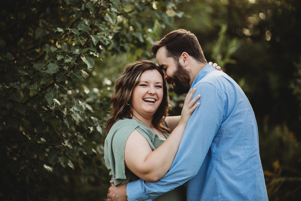 West Lafayette Indiana Couples Session// Evan + Abby - Couple are hugging, woman is looking at the camera with a big smile while the man is whispering in her ear.