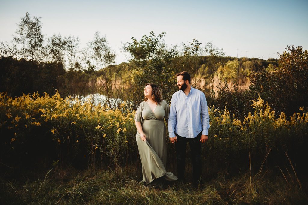 West Lafayette Indiana Couples Session// Evan + Abby - Woman and man standing in front of Goldenrod flowers. Both are smiling. Woman is looking to the left and man is looking at woman.