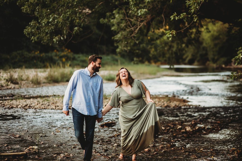 West Lafayette Indiana Couples Session// Evan + Abby - Man guides woman though creek at Fairfield Lakes Park walking hand in hand.