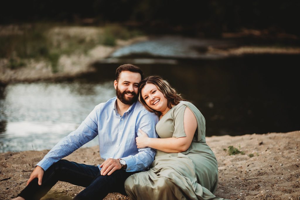 West Lafayette Indiana Couples Session// Evan + Abby - Couple sits on the sandy beach arm in arm looking at the camera with big smiles.