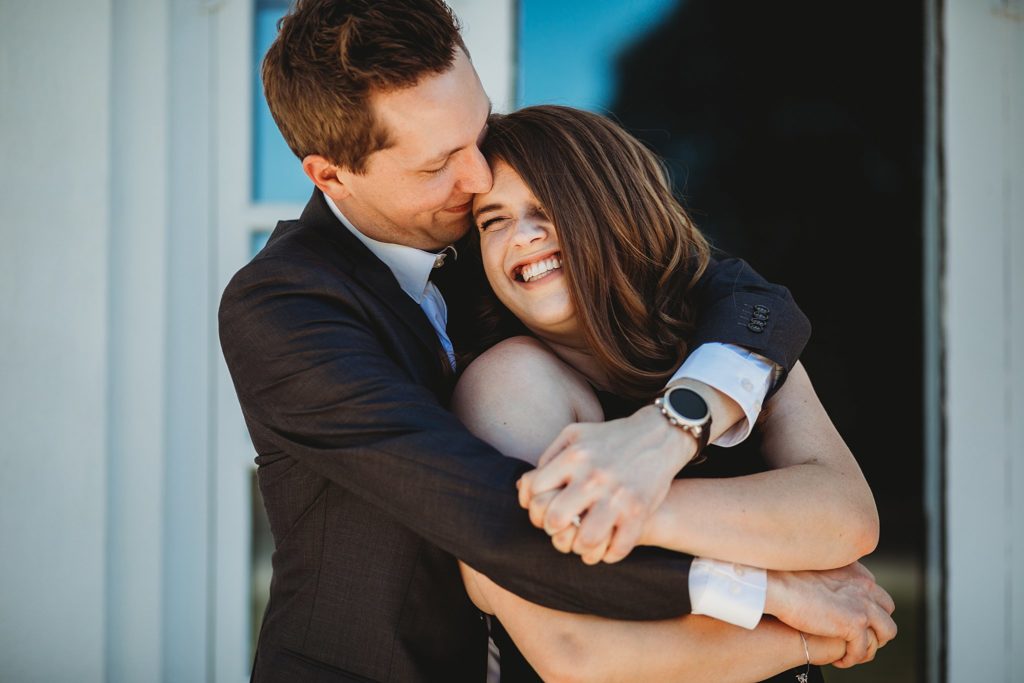 Newfields Engagement Session// Michelle + Adam - Couple cuddles together as man kisses woman's head as she smiles a big smile.