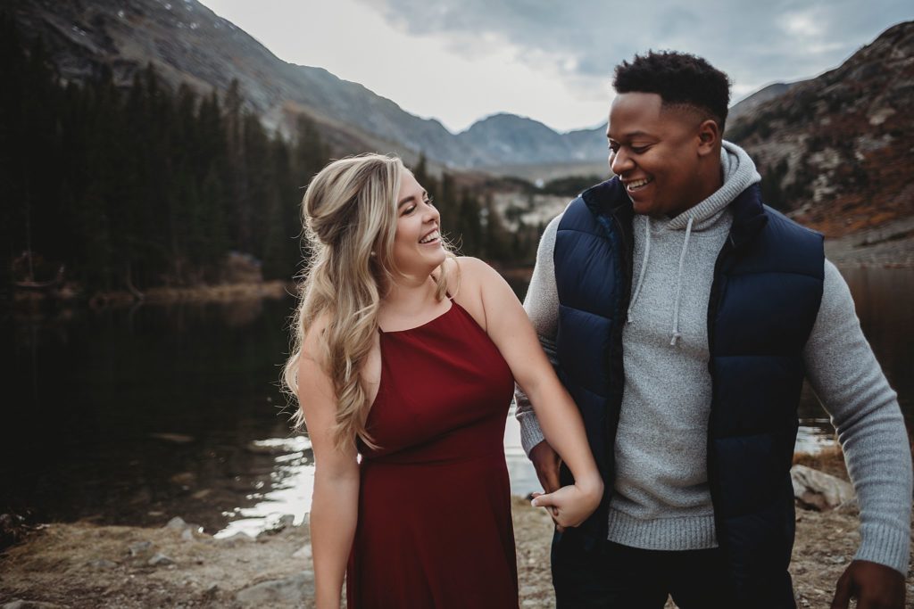 Breckenridge Engagement Session-couple holding hands by lake  and mountains in colorado