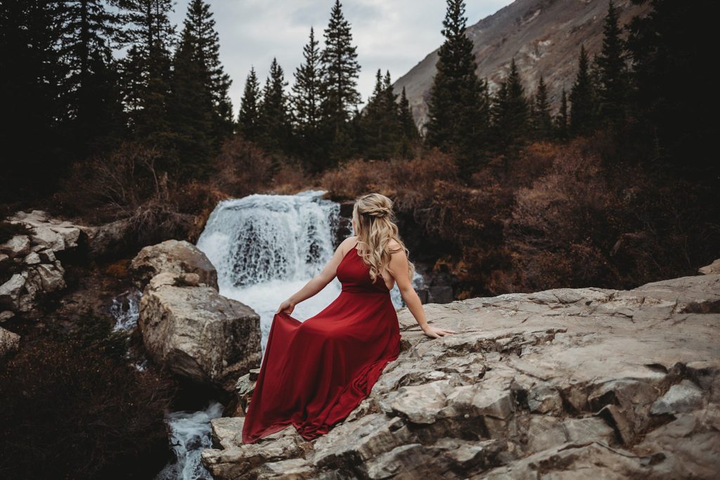 Girl posing on top of rock in front of waterfall in colorado 