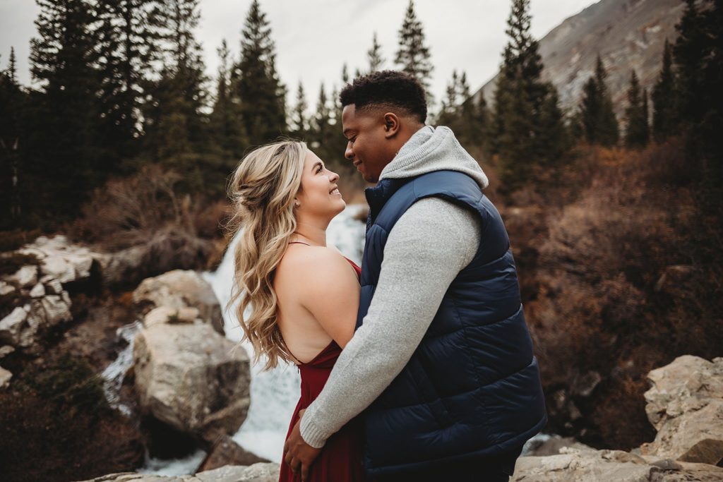 Man holding onto woman in front of a waterfall in colorado photos 