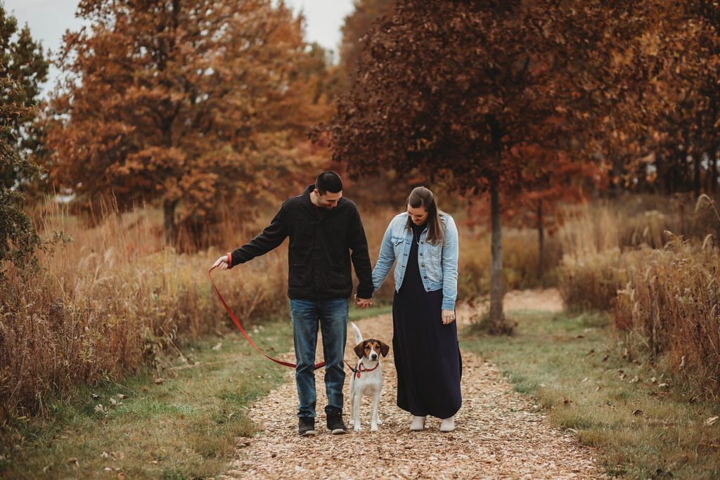 dog stands in the middle of man and woman for their engagement pictures