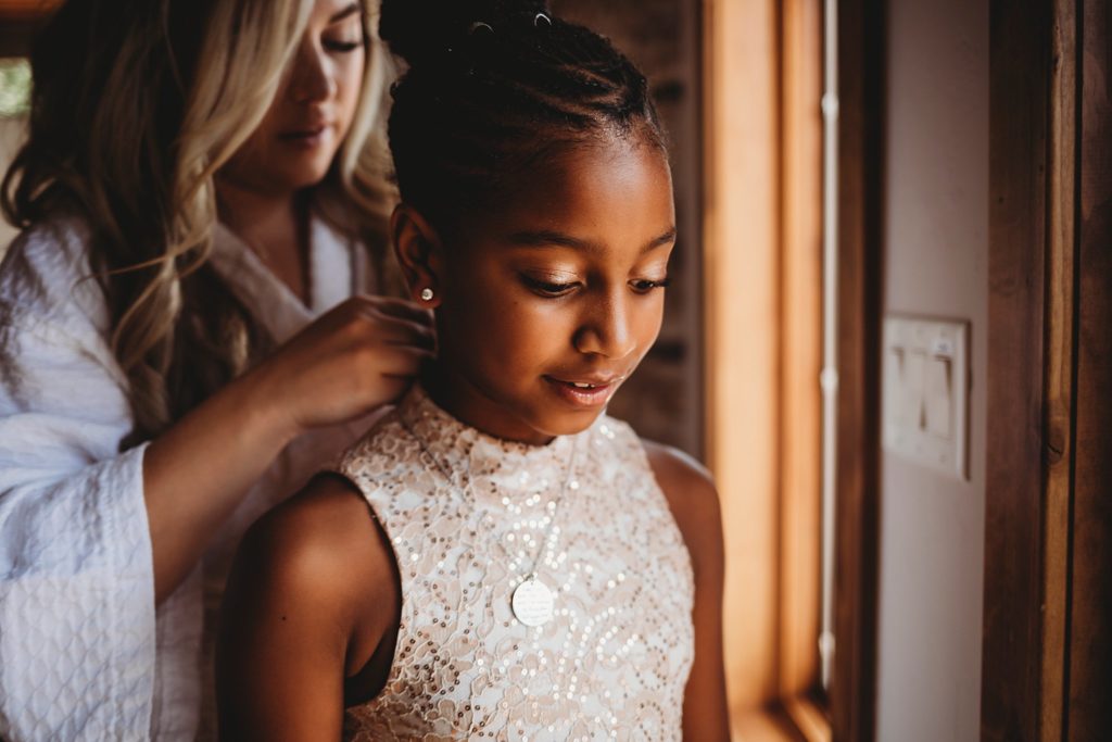 bride putting a necklace on her now step-daughter to include your kids in your elopement