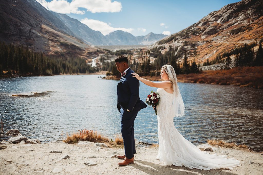 Bride tapping on grooms shoulder during first look at Blue Lakes in Breckenridge Colorado Elopement 