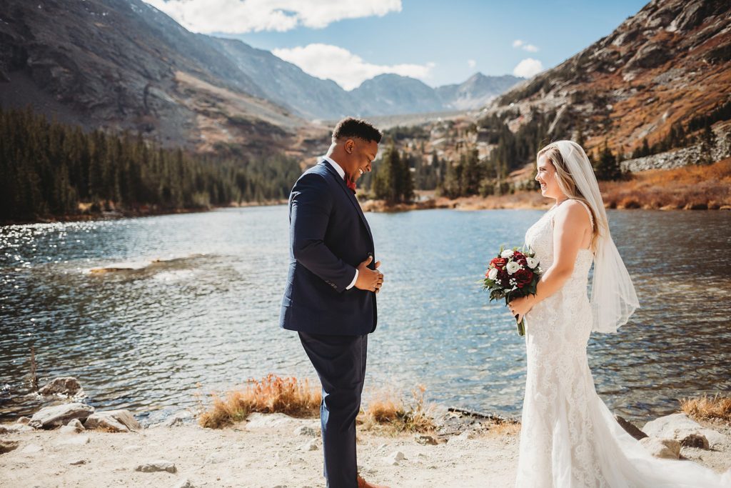 Bride and groom smiling during first look at Blue Lakes in Breckenridge Colorado Elopement 