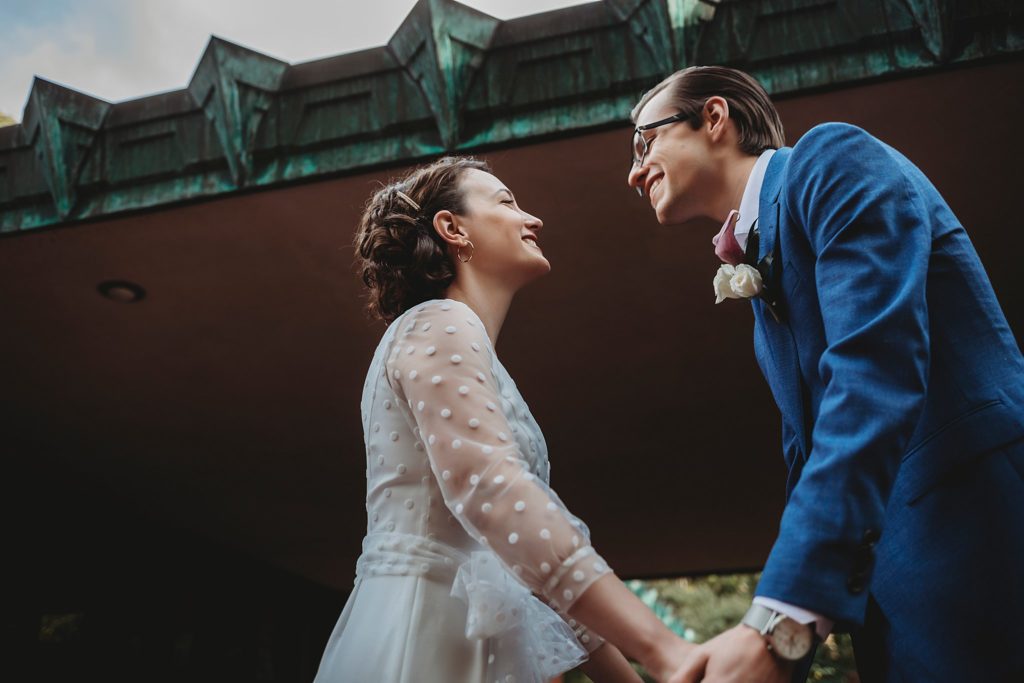 bride and groom smile at each other in front of frank Lloyd wright's samara house 