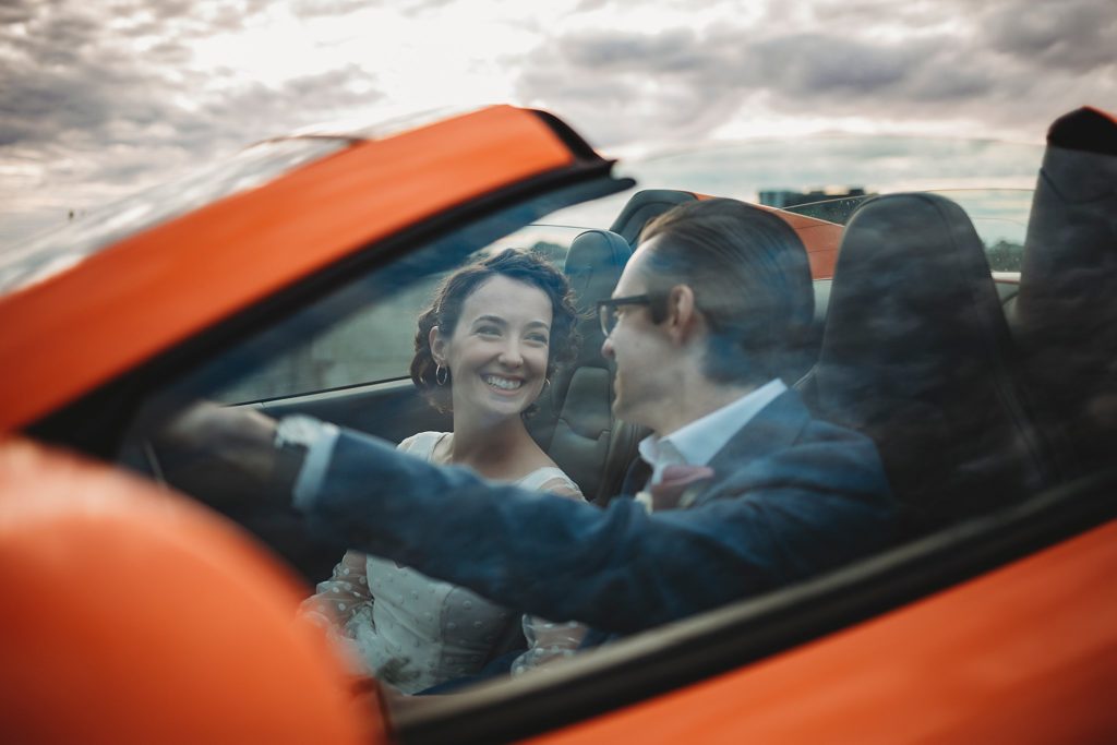 bride and groom pose inside of foreign car in Indiana
