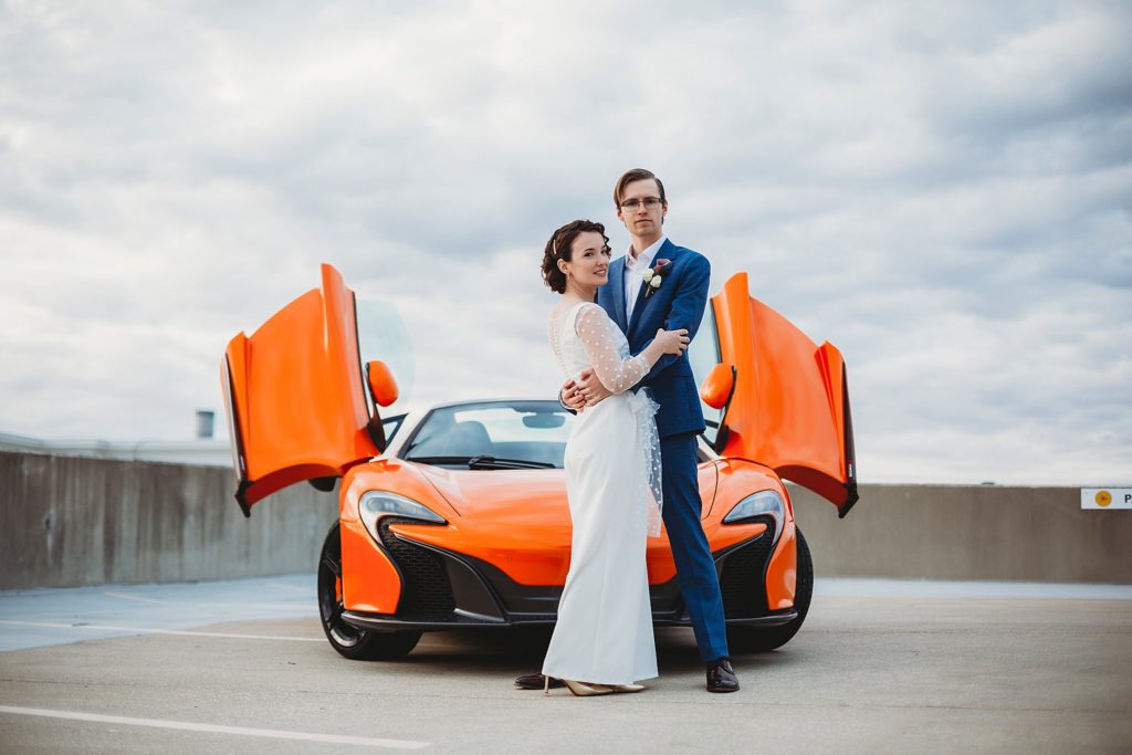classic car rental- bride and groom standing in front of an exotic orange car at their west lafayette indiana elopement
