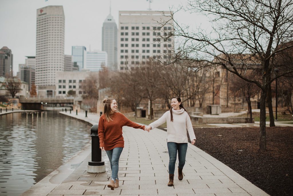 LGBTQ+ Friendly Wedding Vendors- two wives holding hands and looking at one another in downtown Indianapolis at the canal walk