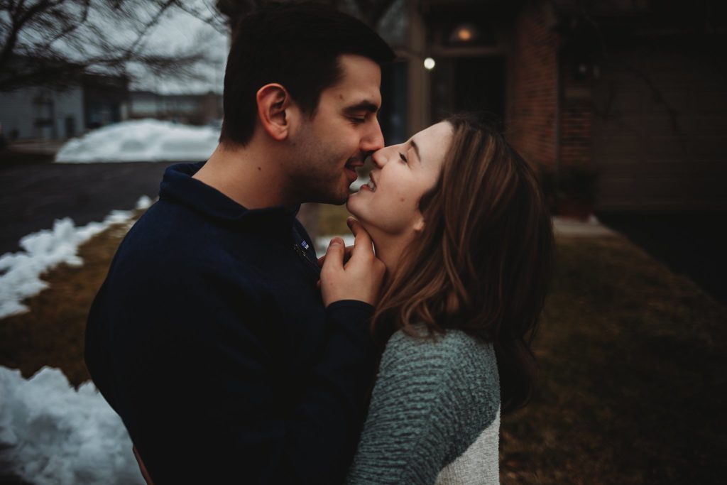 Man holding under woman's chin to lift her chin up for a kiss at their Crown Point Indiana Engagement Session
