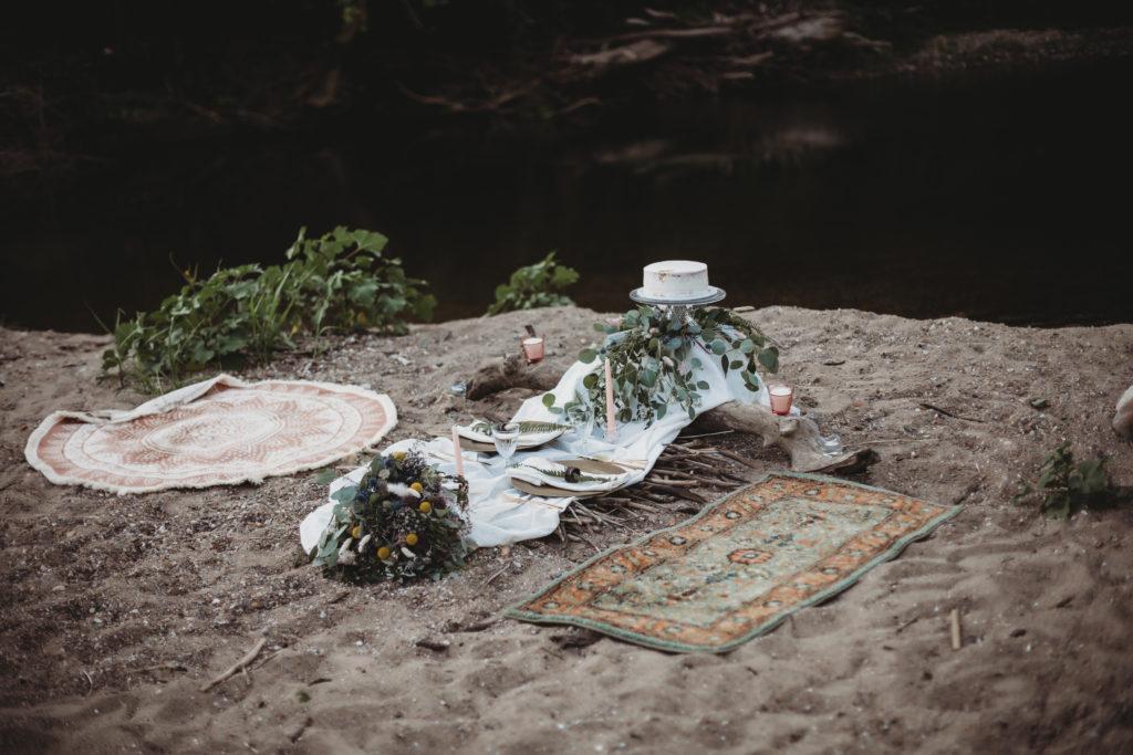 Elope in Indiana - A table spread of an elopement in Indiana elopement on the beach with two rights on either side of a table made of driftwood.