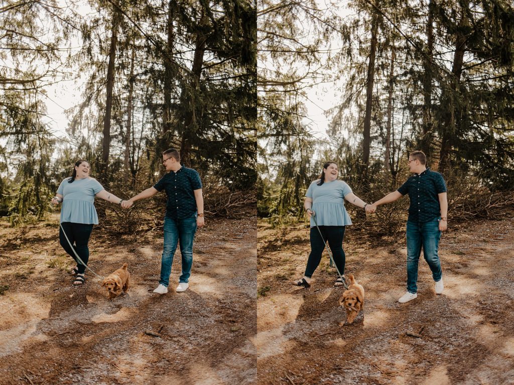 couple walking through the woods holding hands and looking at each other while walking the dog on the leash
