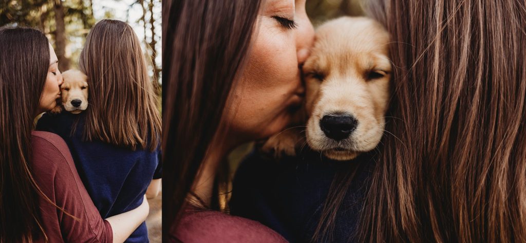 Woman in blue shirt holding puppy over shoulder with back to the camera while girl in red shirt kisses the puppy's head at Purdue horticulture park.