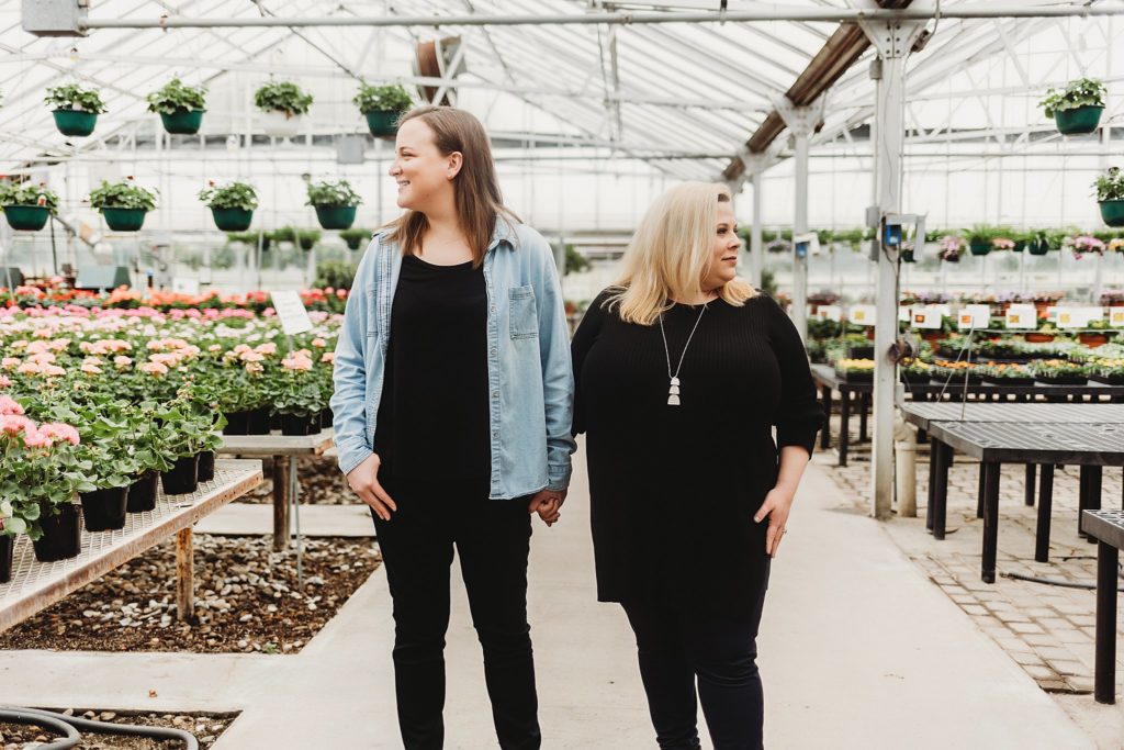 couple standing in the Indiana Greenhouse while looking in opposite directions of each other