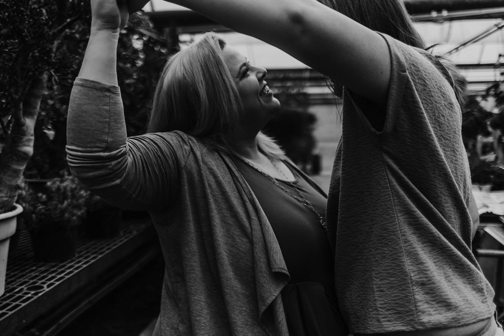 couple holding hands and raising arms together while smiling having fun with photo in black and white