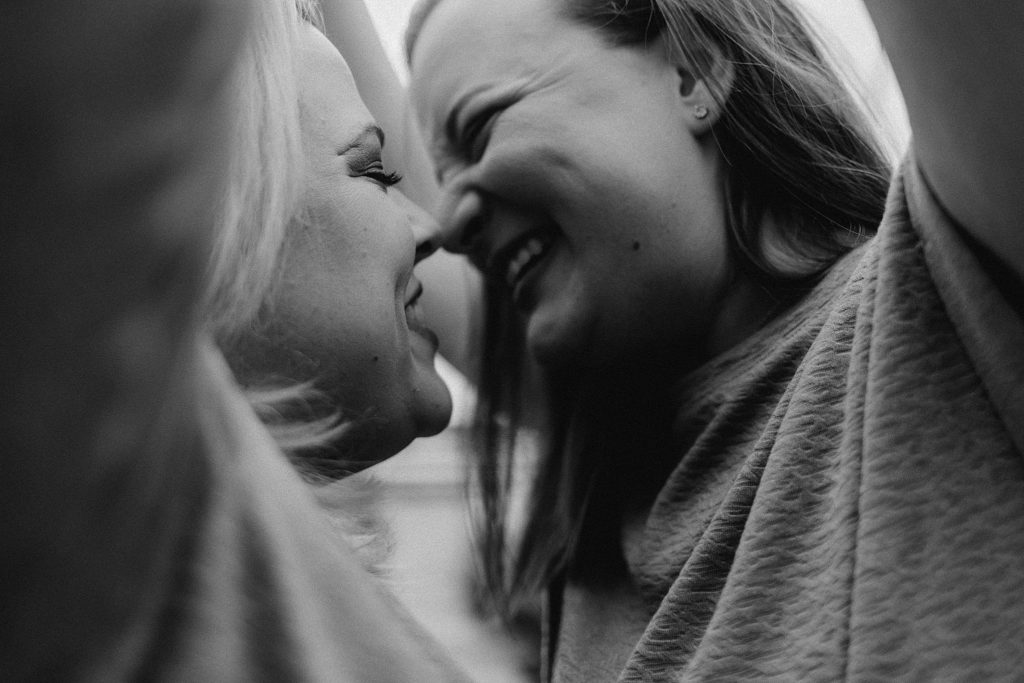 close up of couple smiling at each other while camera angle is below arms which frame the photo and black and white