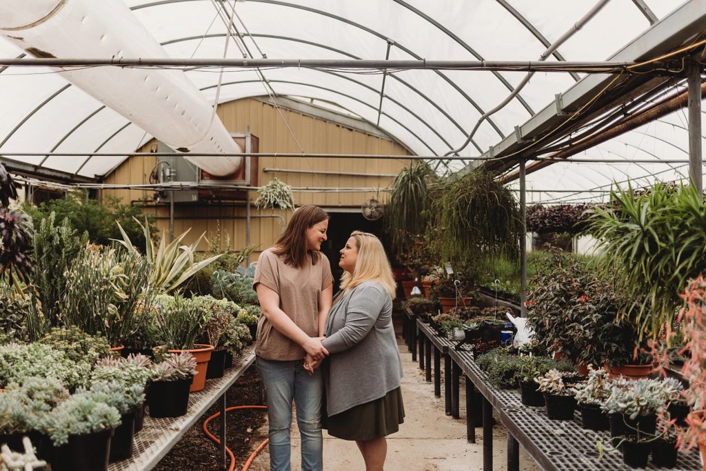 landscape shot of the couple dolding hands and happily looking at each other in the indiana greenhouse