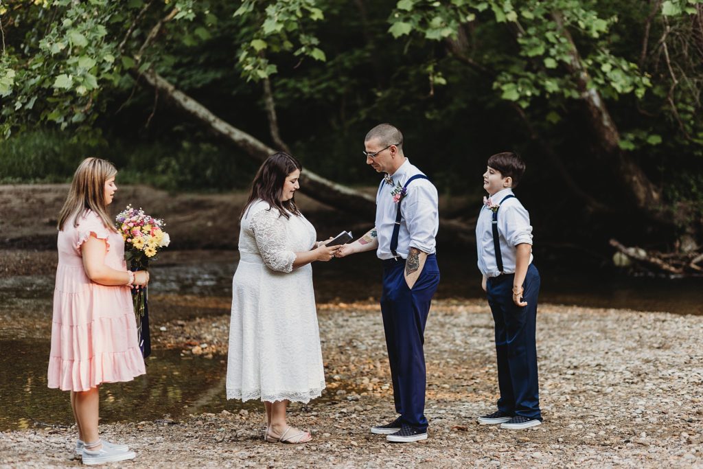 a man and a woman read vows to one another in an Indianapolis park while Eloping in Indiana 