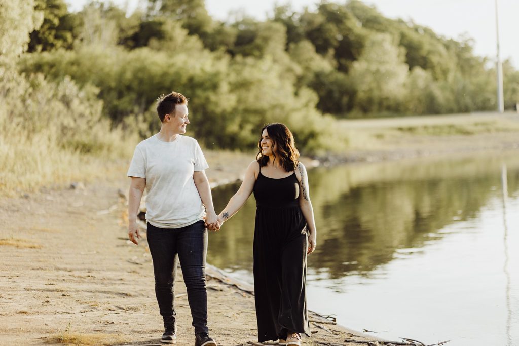 LGBTQ engagement session-two women holding hands in front of a lake looking lovingly into each other's eyes in west lafayette, indiana