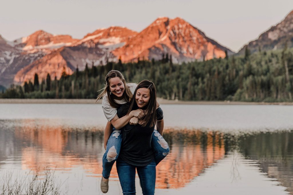 Two women holding onto another another overlooking the mountains at an LGBTQ anniversary session in Utah
