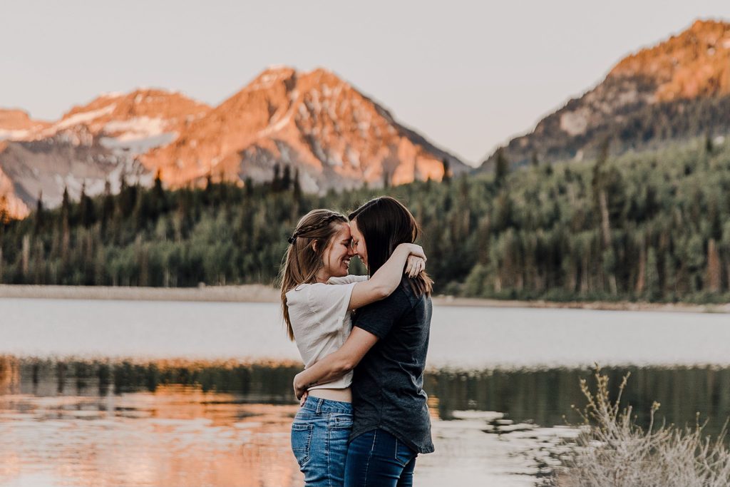 Two women holding onto another another overlooking the mountains at an LGBTQ anniversary session in Utah