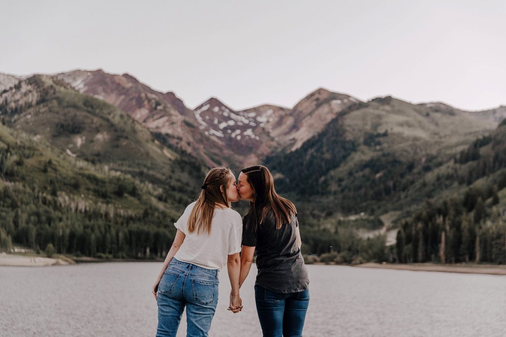 two women kissing at their lgbtq anniversary session in utah with mountains in the background