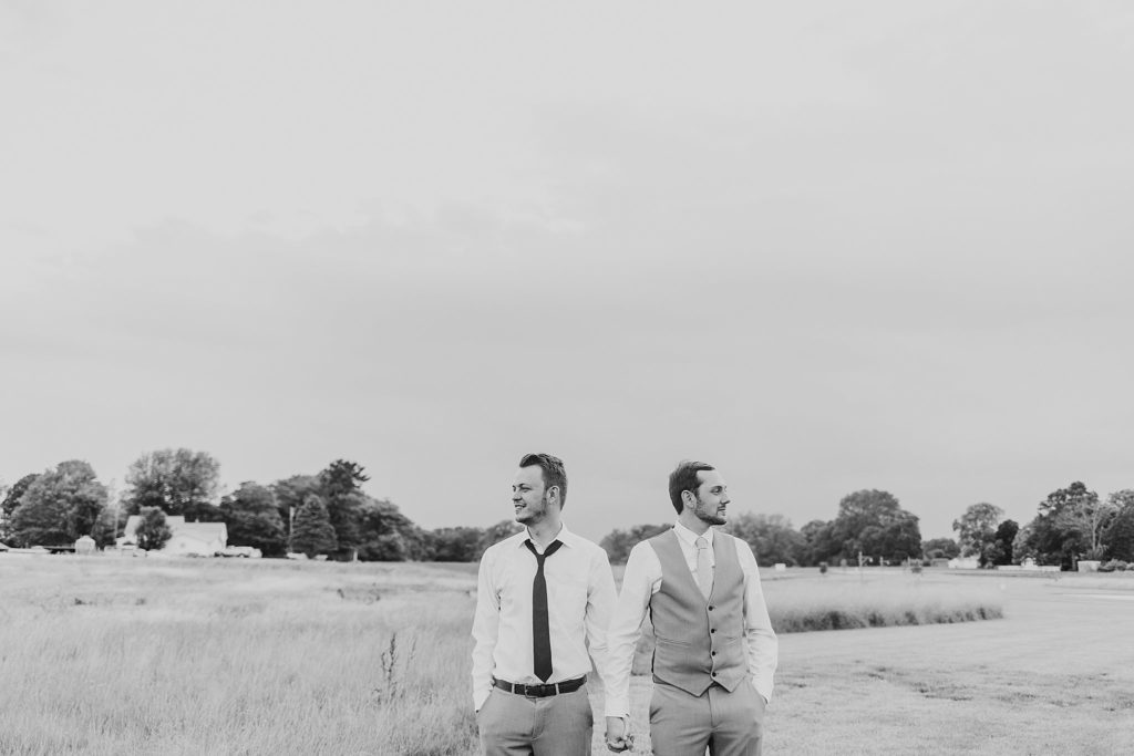 man and man holding hands looking away from each other at their New Journey Farms Wedding