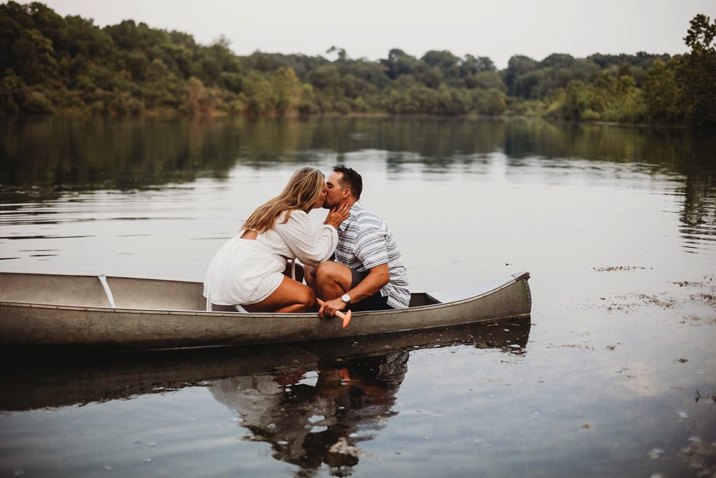 Wife kisses husband as they sit in their canoe on the lake at Fairfield Lakes Park in Lafayette, Indiana at their Indiana Couples Session