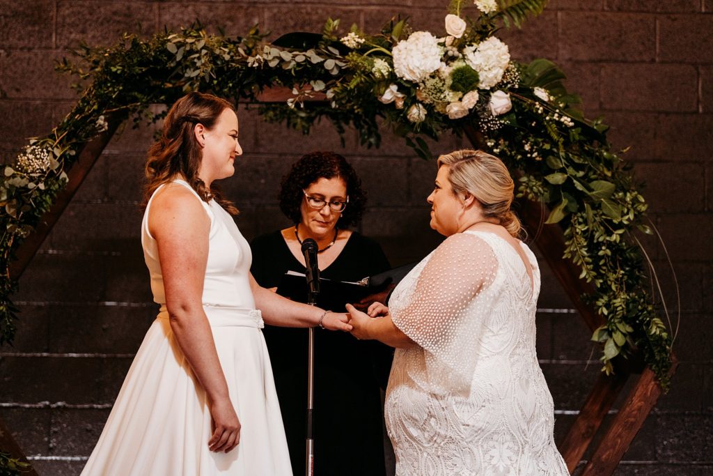lgbtq weddings - LGBTQ couple holding hands and exchanging rings at their indiana wedding