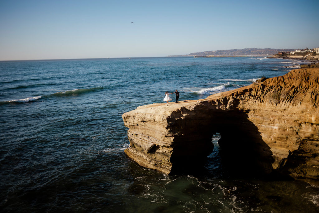 couple dancing on a large rock called sunset cliffs in front of the beach in San Diego california at their California elopement 