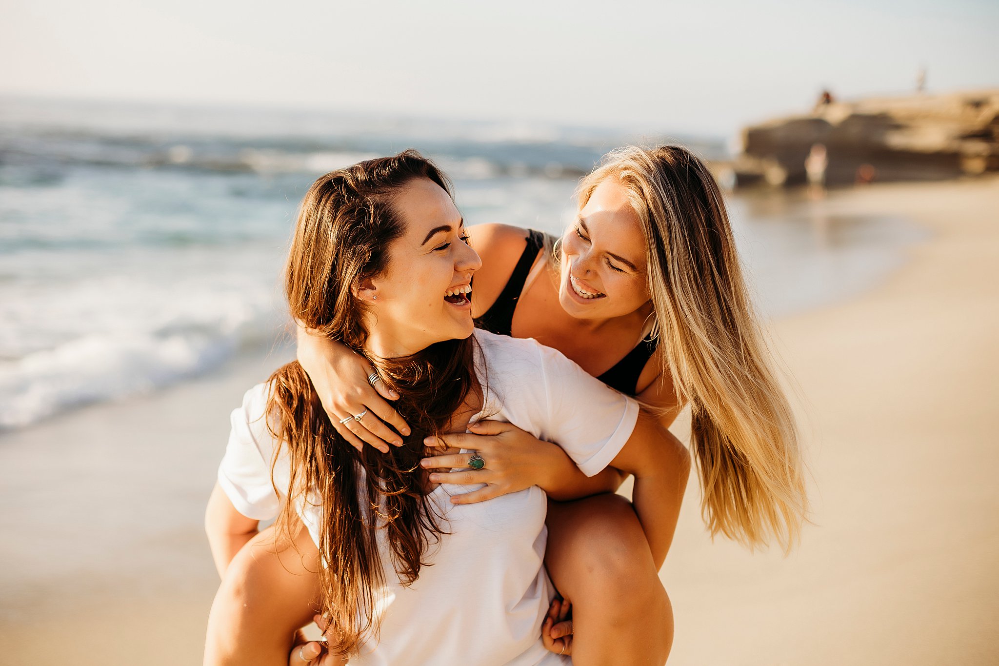 two women holding onto one another at the beach at their La Jolla California Couples Session