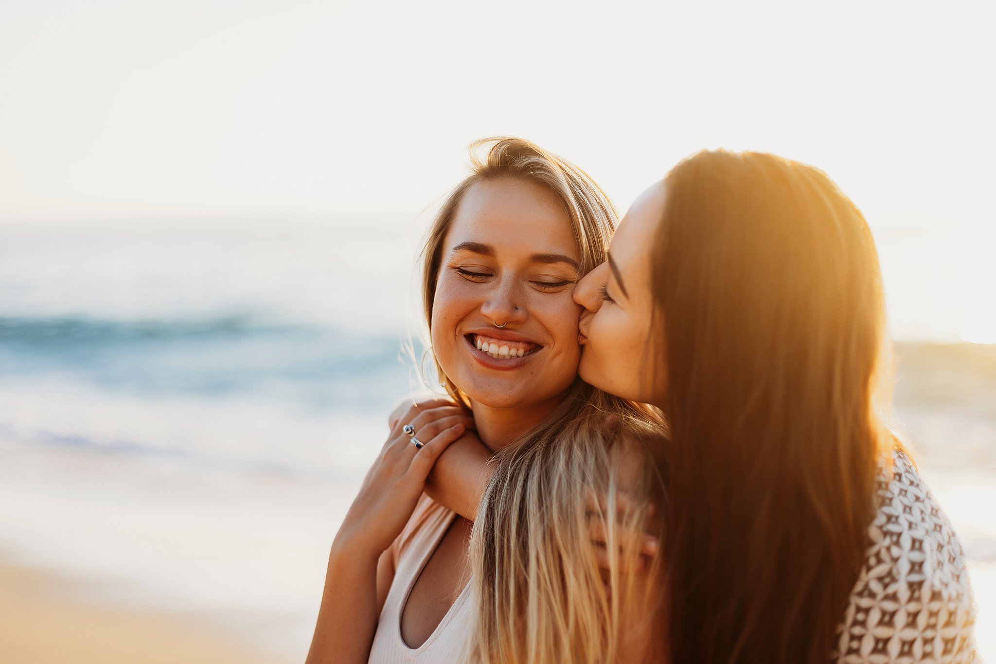 two women sitting in the sand kissing at their La Jolla California Couples Session