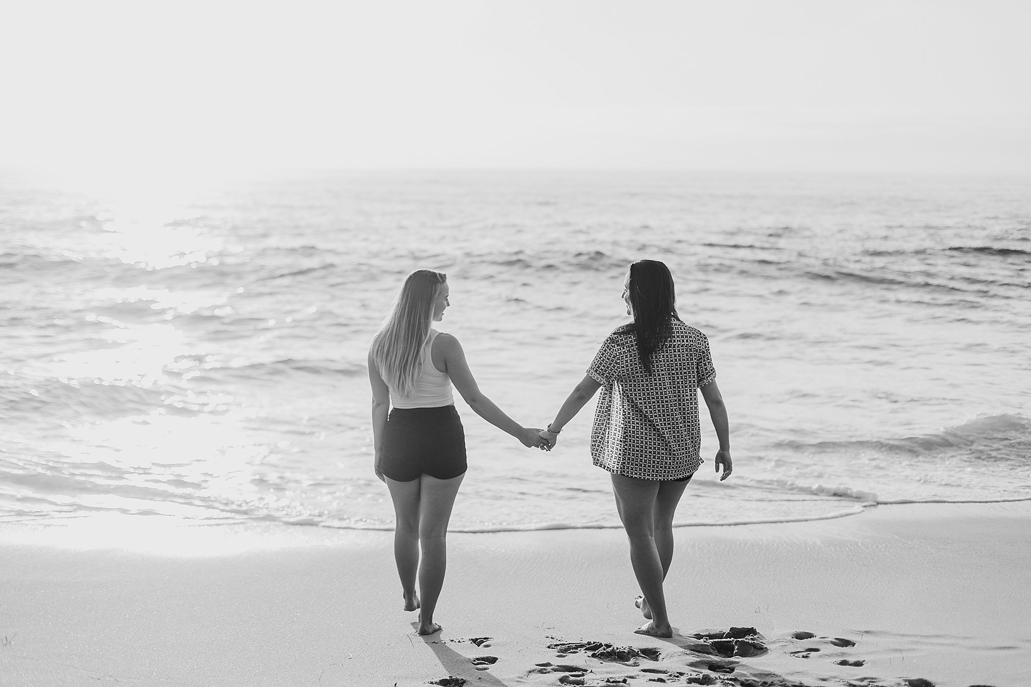 two women holding hands along the beach at their La Jolla California Couples Session