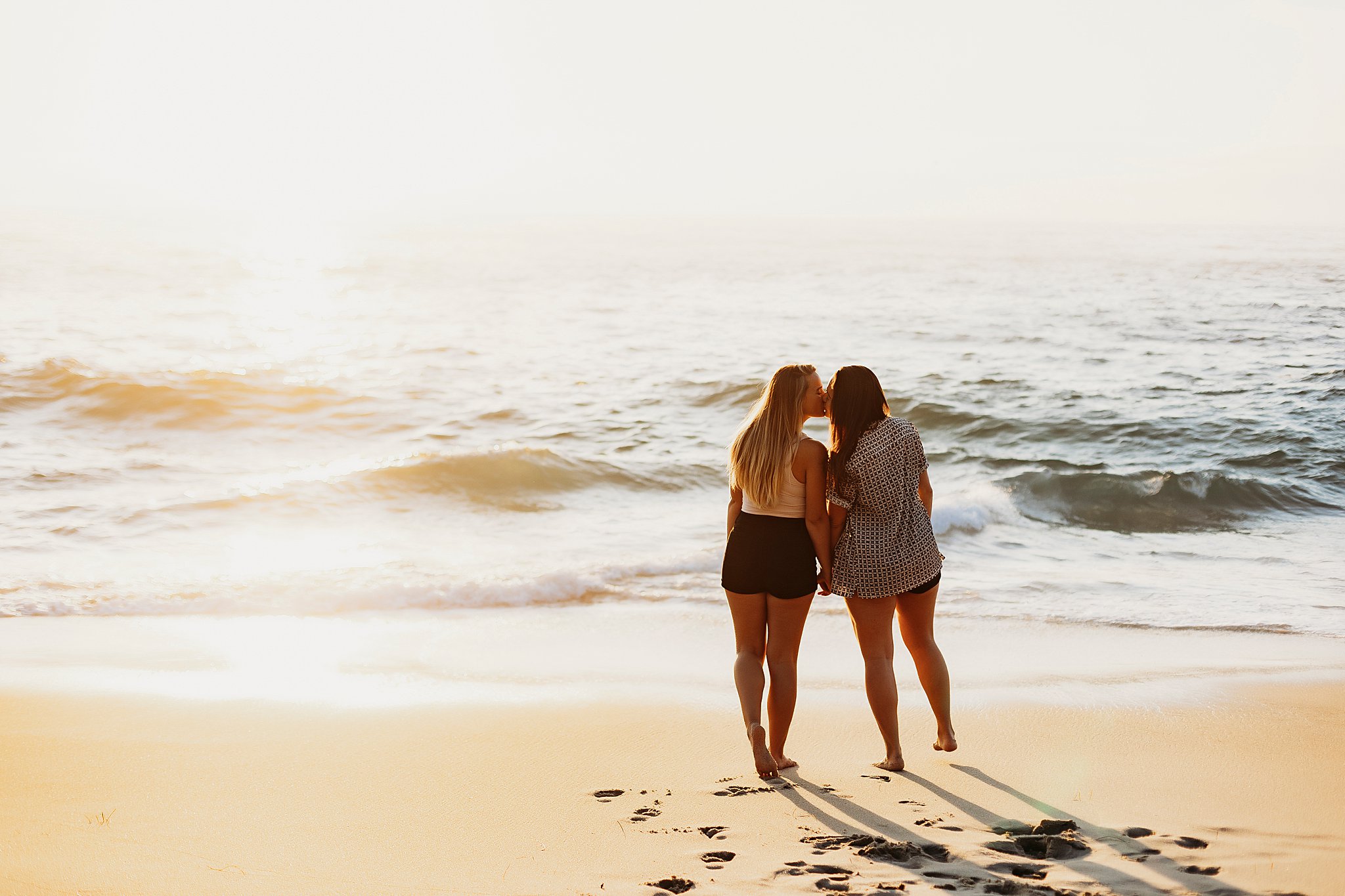 two women holding hands along the beach at their La Jolla California Couples Session
