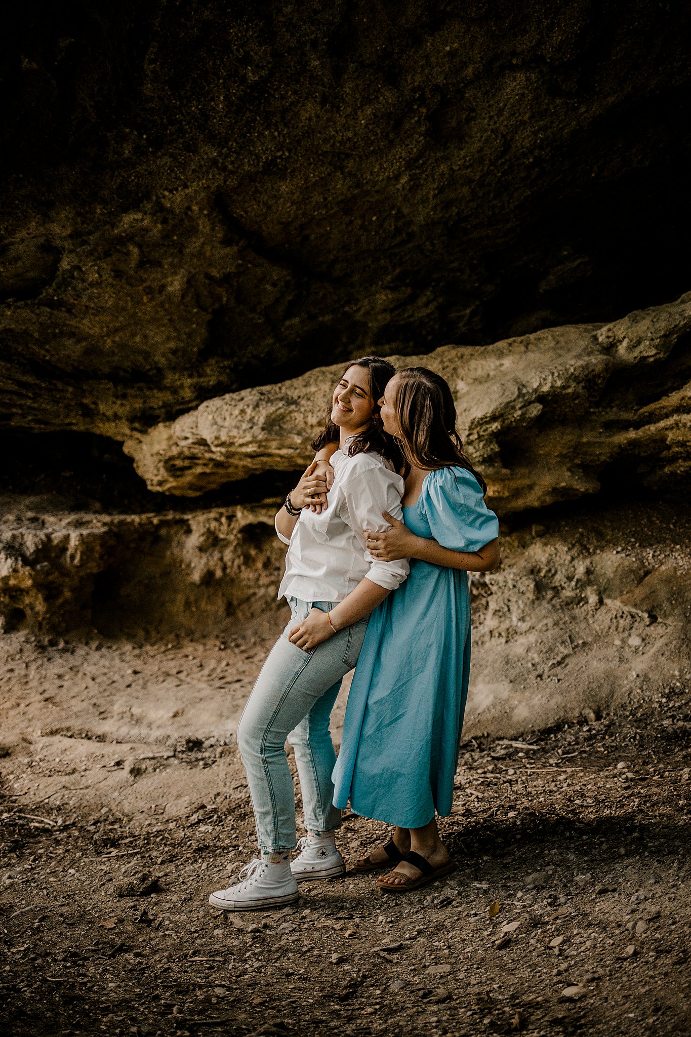 Samantha Mitchell, an LGBTQ Engagement photographer captures two women at Prophet's Rock in Indiana. The two women are snuggling together amongst large rocks. They are kissing.