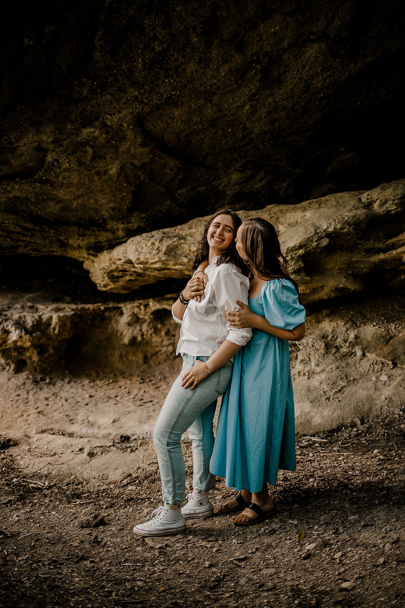 Samantha Mitchell, an LGBTQ Engagement photographer captures two women at Prophet's Rock in Indiana. The two women are snuggling together amongst large rocks. They are kissing.