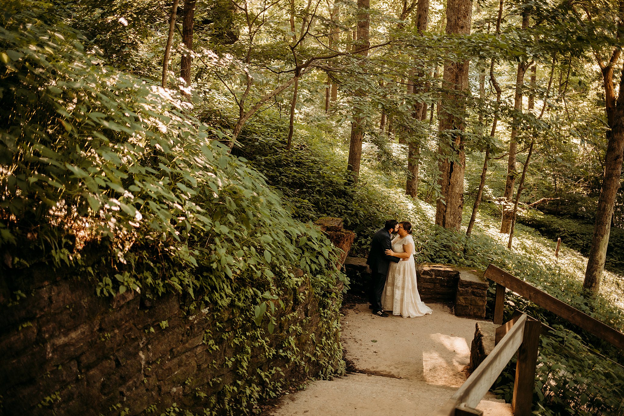 A man and a woman give each other a kiss while being surrounded with large rock and big trees at their Turkey Run Elopement