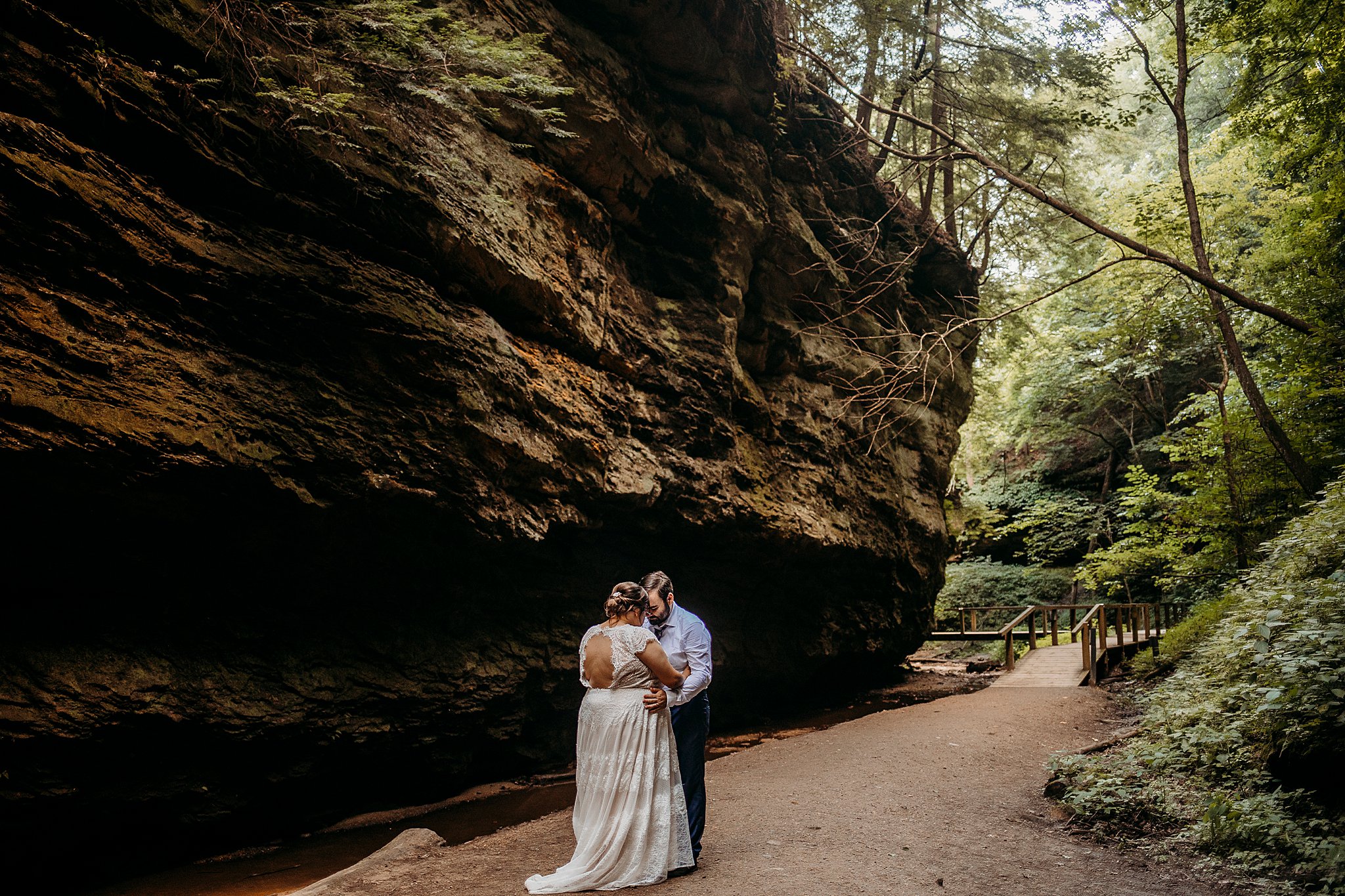 A man and a woman lean their foreheads together while being surrounded with large rock and big trees at their Turkey Run Elopement