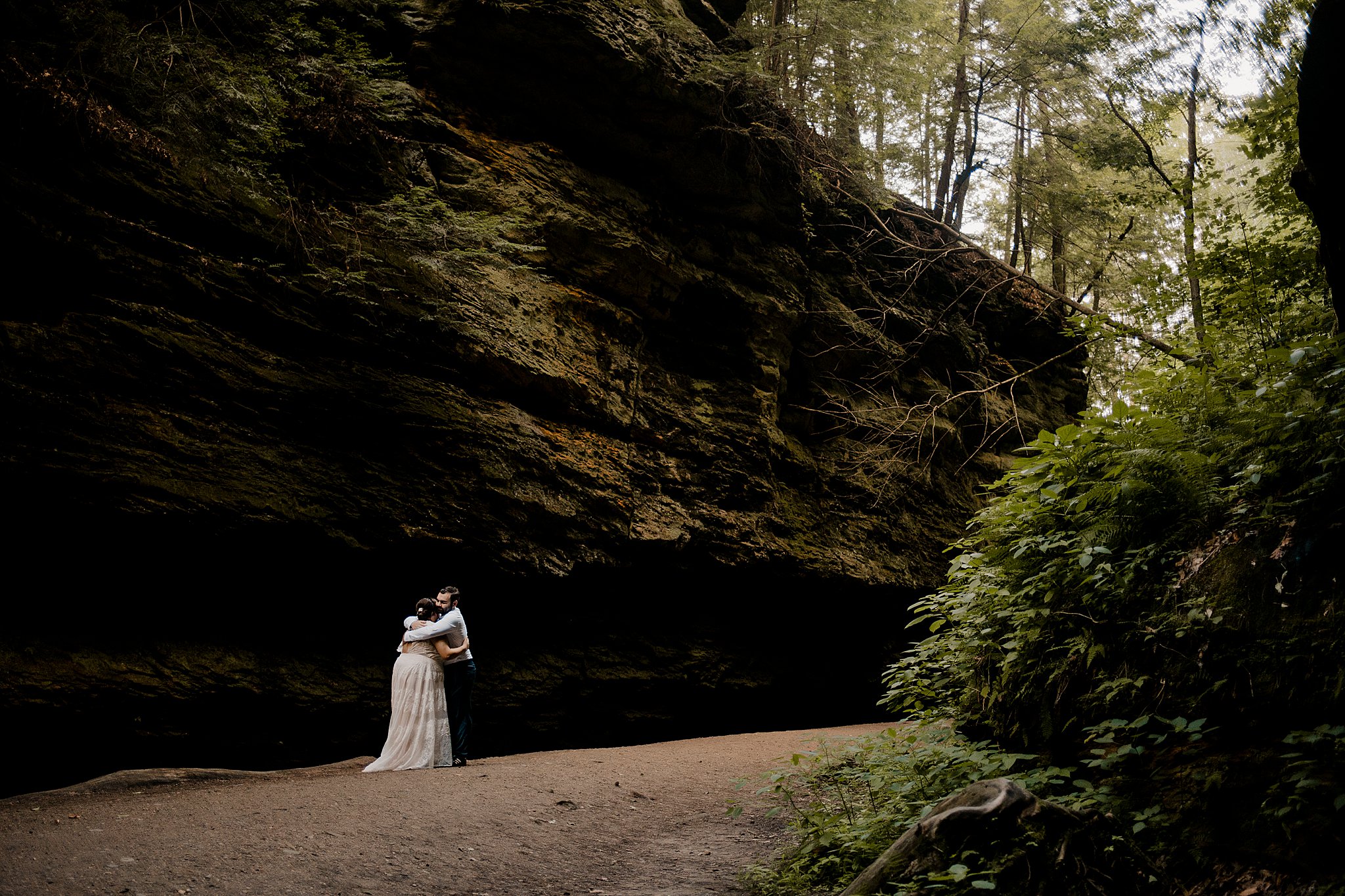 A man and a woman give each other a hug while being surrounded with large rock and big trees at their Turkey Run Elopement