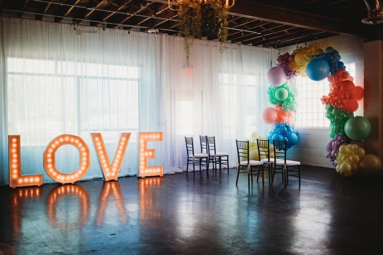 The Ivory Foundry located in Indianapolis is the perfect Small Wedding Venue in Indiana. Balloon arch, love sign, and 6 chairs are located in a beautifully lit space. 