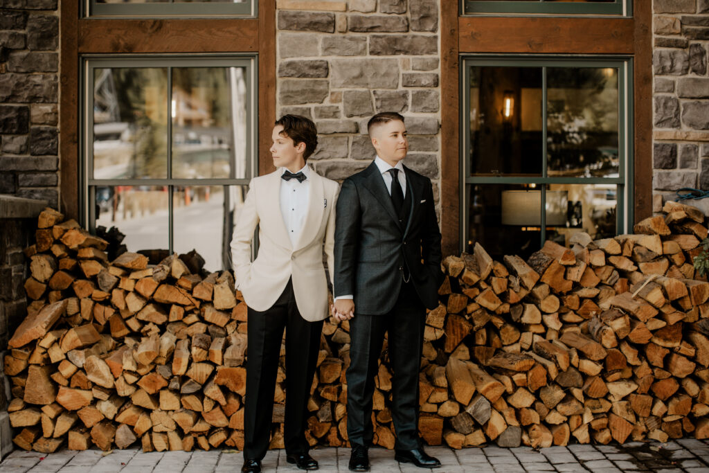 lgbtq+ couple, looking away from each other while holding hands in front of a pile of wood and deciding why eloping is the perfect choice for lgbtq+ couples. 